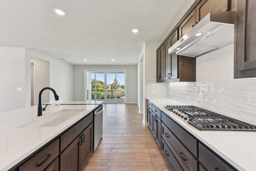 Kitchen featuring under cabinet range hood, light wood finished floors, recessed lighting, stainless steel appliances, and light stone counters