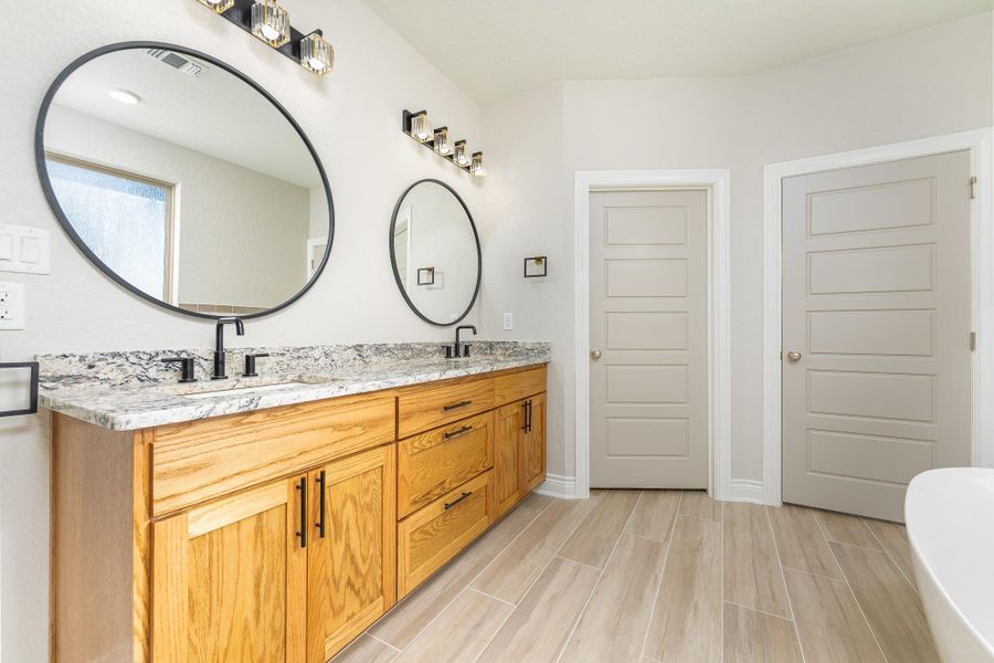 Bathroom with double vanity, a freestanding tub, and wood finish floors Bathroom with double vanity, a freestanding tub, and wood finish floors