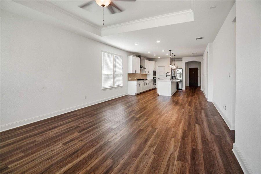 An open-concept living area with lustrous hardwood flooring flows seamlessly into a contemporary kitchen.