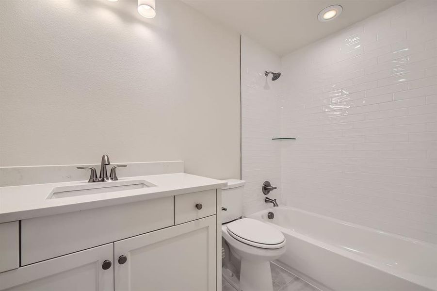 Full bathroom with vanity, toilet, and tiled shower / bath combo