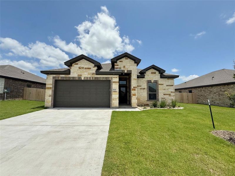 View of front of home with stone siding, concrete driveway, and an attached garage