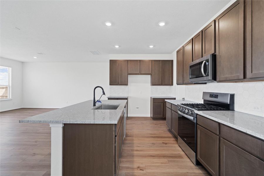 This spacious kitchen boasts soaring ceilings, Woodmont Dakota Shaker cabinets in a Smolder stain, Granite Summit White countertops, stainless steel Whirlpool appliances, a modern Daltile backsplash, recessed lighting, an extended breakfast bar countertop, and a pantry—all overlooking the expansive Great Room. This spacious kitchen boasts soaring ceilings, Woodmont Dakota Shaker cabinets in a Smolder stain, Granite Summit White countertops, stainless steel Whirlpool appliances, a modern Daltile backsplash, recessed lighting, an extended breakfast bar countertop, and a pantry—all overlooking the expansive Great Room.