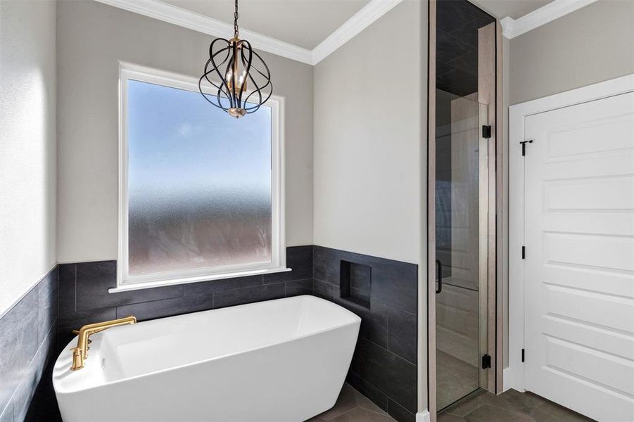 Bathroom featuring tile patterned flooring, a notable chandelier, ornamental molding, and separate shower and tub