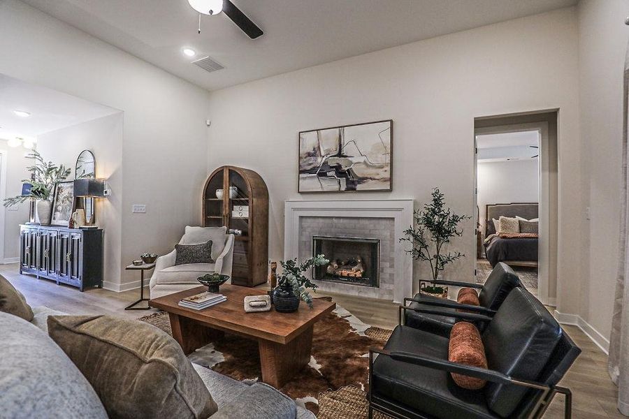 Living room with wood finished floors, a brick fireplace, and ceiling fan