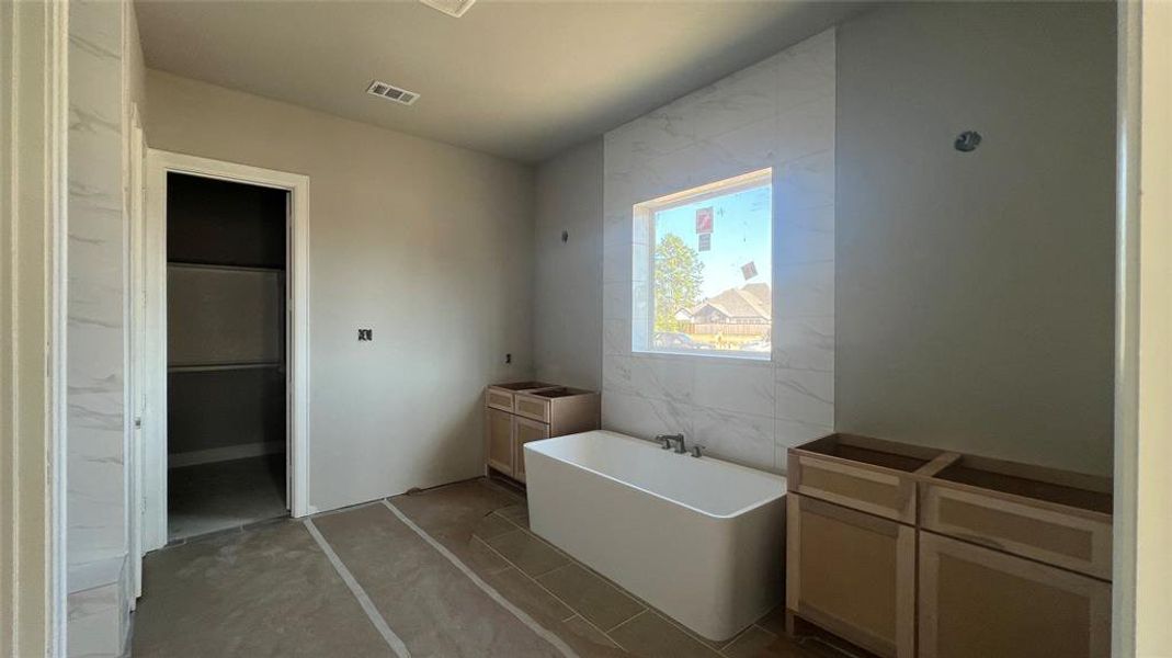 Primary Bathroom featuring dual vanities and a freestanding tub