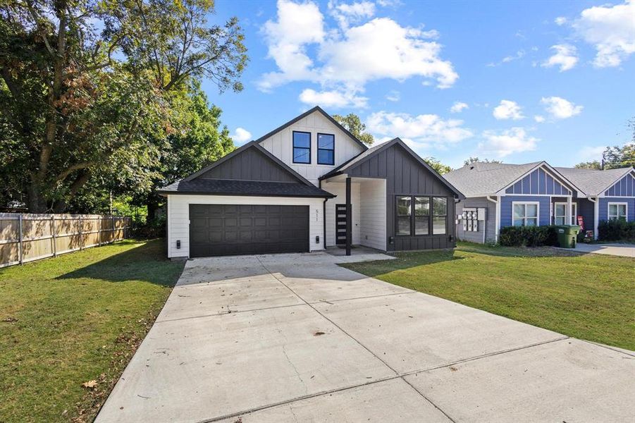 Modern farmhouse with board and batten siding, concrete driveway, and a shingled roof