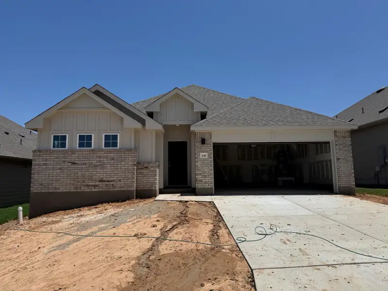 View of front facade featuring brick siding, an attached garage, driveway, board and batten siding, and roof with shingles View of front facade featuring brick siding, an attached garage, driveway, board and batten siding, and roof with shingles