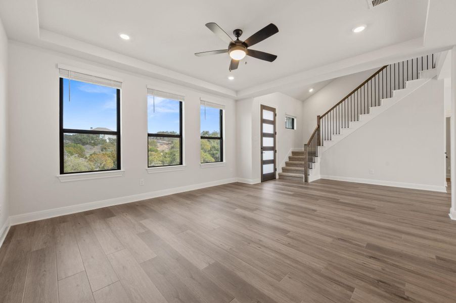 Luxurious open concept floor plan featuring wood-look tile planks, oversized glass sliders, and a grand staircase