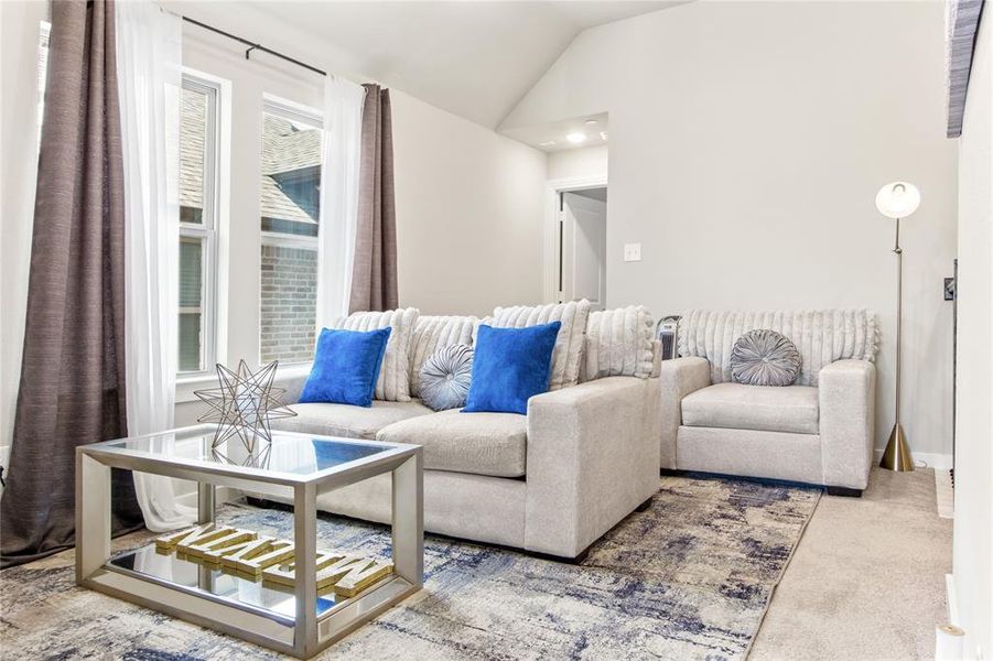 Living room with a wealth of natural light, vaulted ceiling, and carpet floors