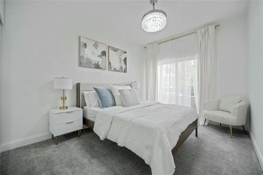 Bedroom with a chandelier, dark carpet, and baseboards