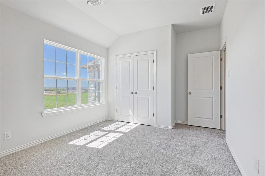 Unfurnished bedroom featuring light carpet, vaulted ceiling, and a closet