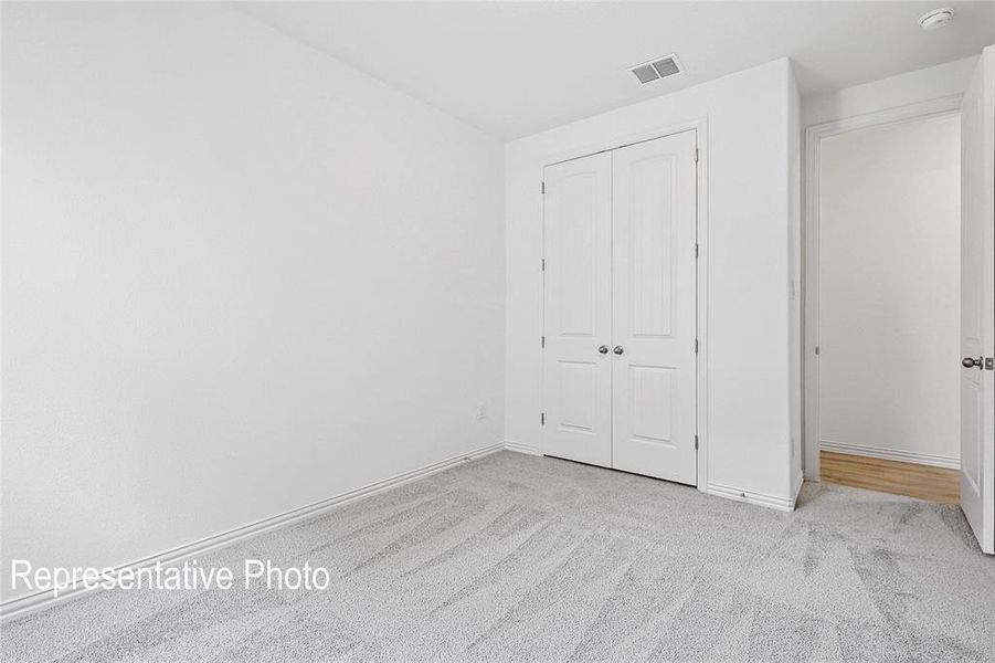 Carpeted interior space featuring light gray walls, white trim, and a white bi-fold door