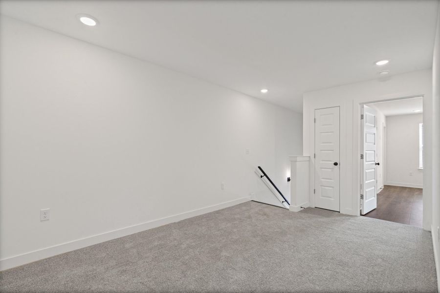 Recessed lighting, plush carpeting, bright white walls, crisp white trim, and a paneled door