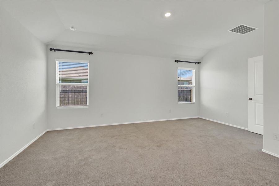 A spacious, naturally illuminated room featuring soft carpeting and a simple, clean aesthetic.