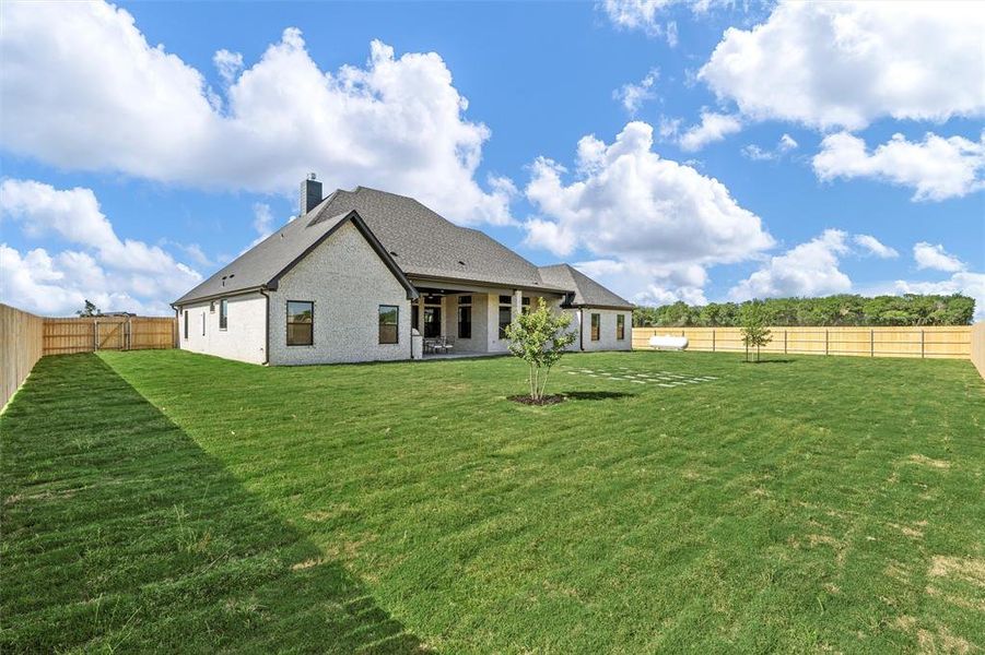 Back of house with a chimney, a fenced backyard, brick siding, and a patio