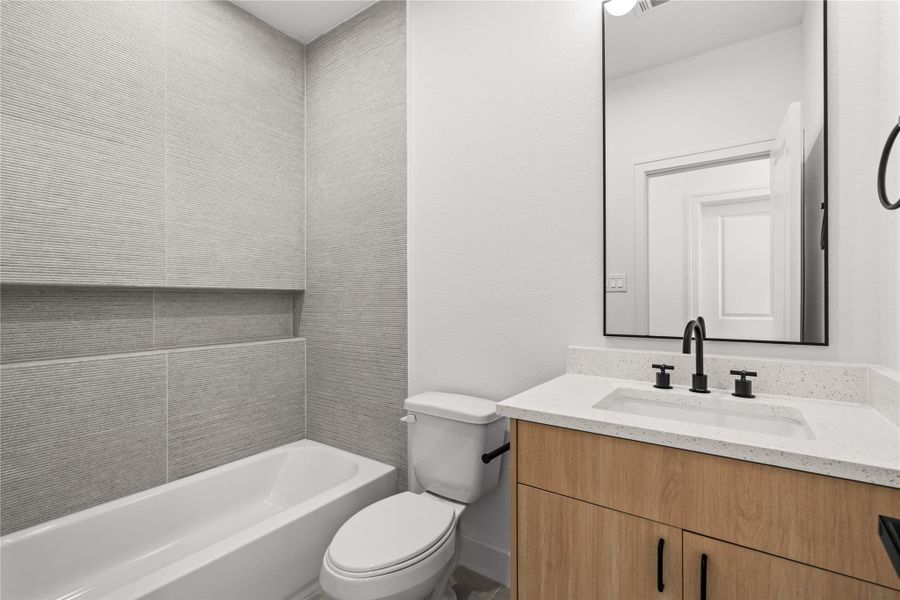 The adjacent full bathroom features a wood vanity with a white quartz countertop, an under-mount sink, and a black-framed mirror. A black gooseneck faucet pairs with the mirror, while the shower-tub combination is lined with neutral horizontal tiles.