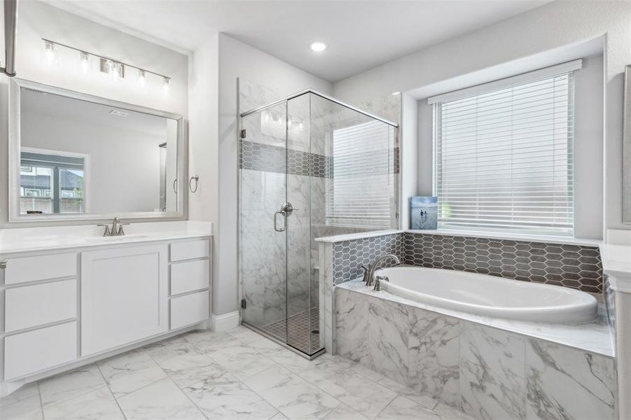 Full bathroom featuring a bath, a marble finish shower, vanity, light marble finish floors, and plenty of natural light