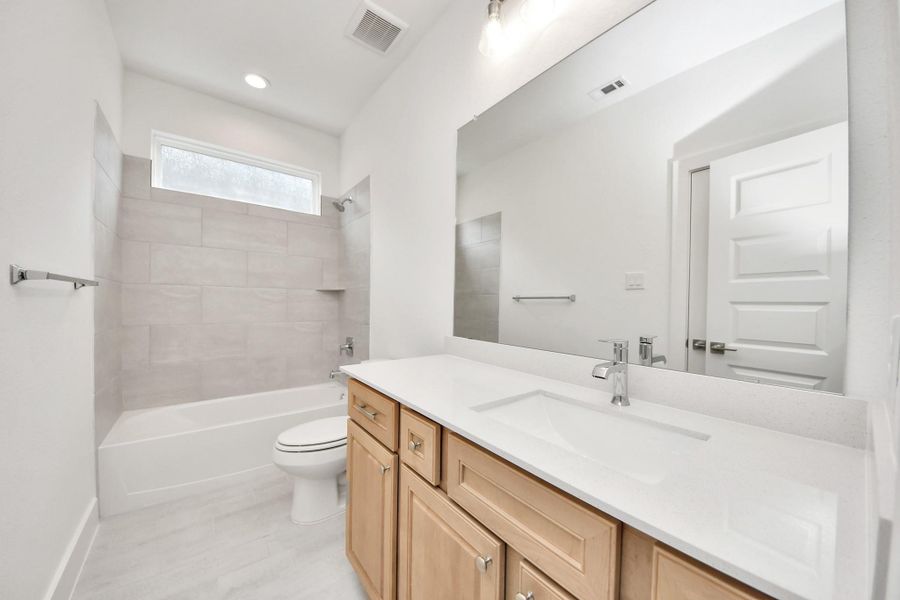Secondary bath features tile flooring, bath/shower combo with tile surround, light stained wood cabinets, beautiful light countertop. Secondary bath features tile flooring, bath/shower combo with tile surround, light stained wood cabinets, beautiful light countertop.