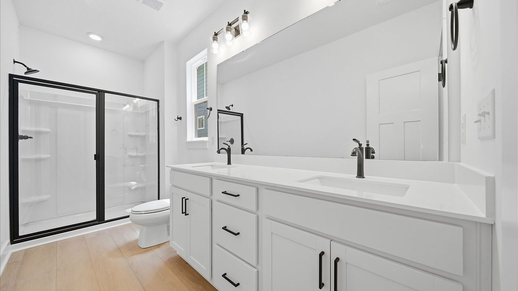 Elegant primary bathroom featuring a spacious walk-in shower and dual vanity in this first-class DRB Homes design Elegant primary bathroom featuring a spacious walk-in shower and dual vanity in this first-class DRB Homes design