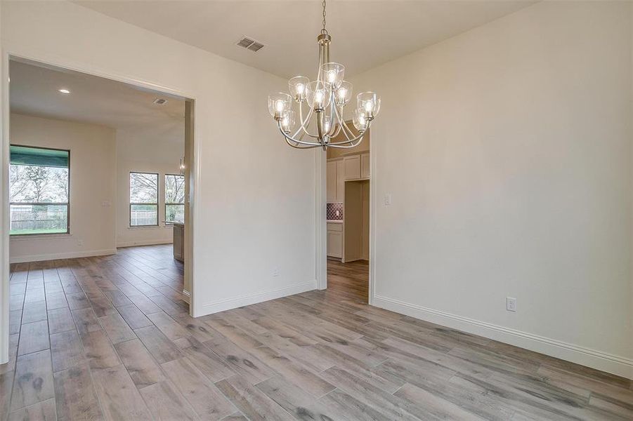 Unfurnished room featuring light wood-type flooring and a notable chandelier