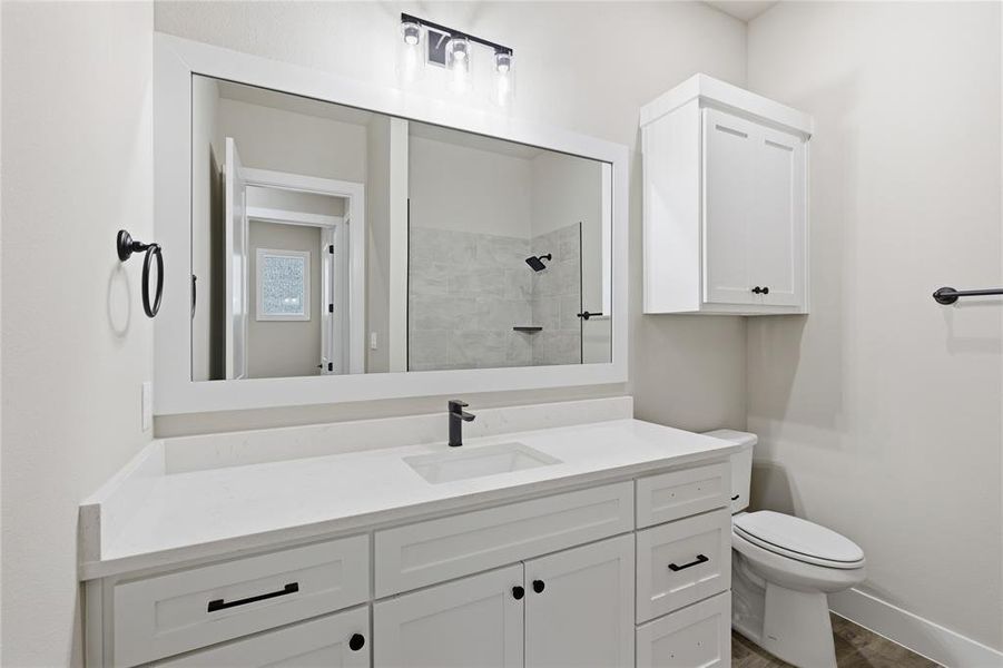Contemporary bathroom featuring an expansive single vanity with a white countertop and integrated sink, matte black faucet, and a large framed mirror Contemporary bathroom featuring an expansive single vanity with a white countertop and integrated sink, matte black faucet, and a large framed mirror