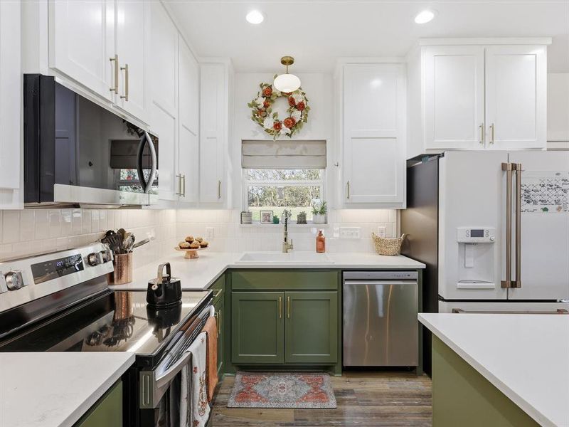 Kitchen with green cabinetry, white cabinets, and recessed lighting