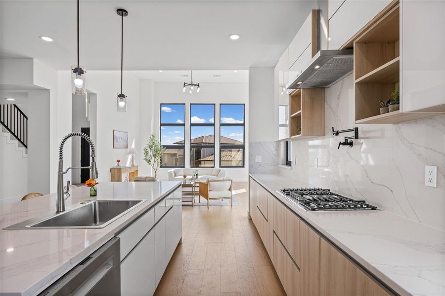 Two tone kitchen featuring light stone countertops, light wood finished floors, modern cabinets, dual tone cabinets, and decorative backsplash