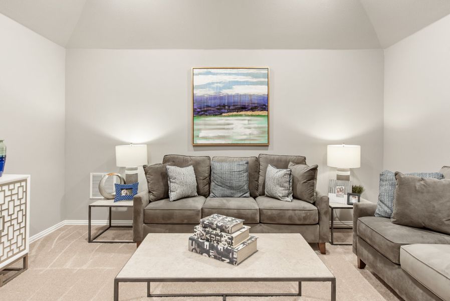 Living room with gray sofa, vaulted ceiling, and abstract wall art above a square coffee table
