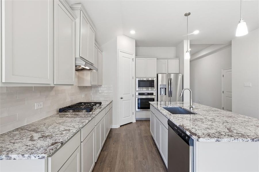 Kitchen featuring a center island with sink, stainless steel appliances, dark wood finished floors, tasteful backsplash, and white cabinetry Kitchen featuring a center island with sink, stainless steel appliances, dark wood finished floors, tasteful backsplash, and white cabinetry