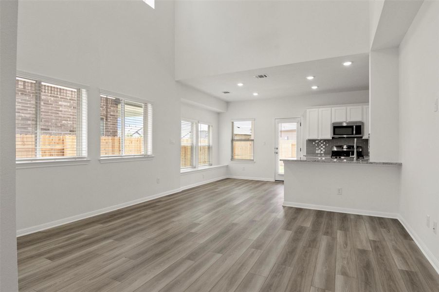 Unfurnished living room with recessed lighting, wood finished floors, and a high ceiling