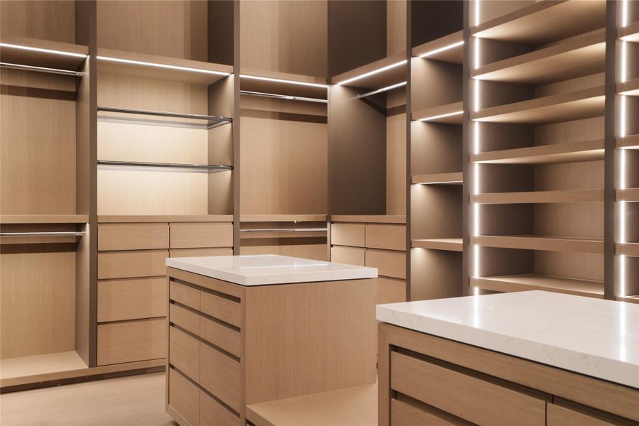 Primary closet with finely crafted millwork and feature lighting throughout