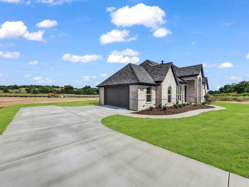 French country inspired facade with brick siding, concrete driveway, a garage, and a front lawn French country inspired facade with brick siding, concrete driveway, a garage, and a front lawn