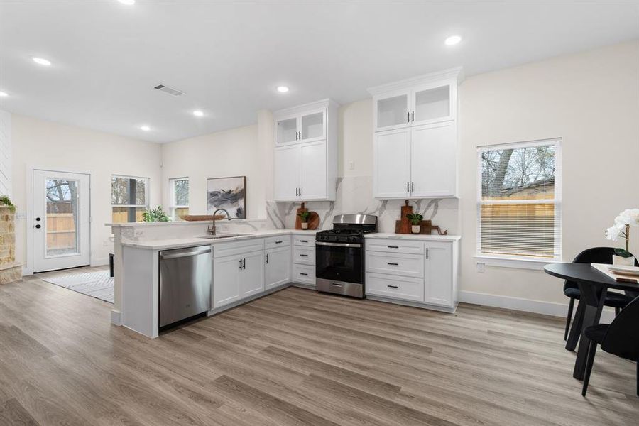 Kitchen with white cabinets, sink, appliances with stainless steel finishes, light hardwood / wood-style floors, and kitchen peninsula