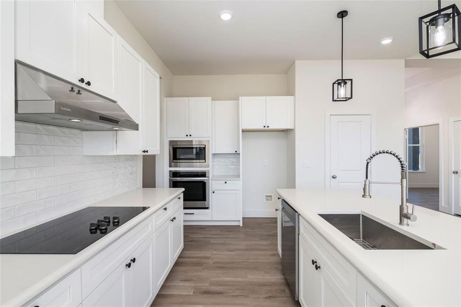 Kitchen featuring pendant lighting, white cabinets, sink, and stainless steel appliances