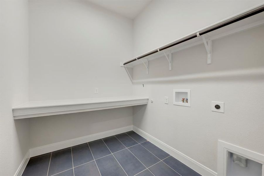 Laundry area with hookup for a washing machine, electric dryer hookup, dark tile patterned flooring, and hookup for a gas dryer
