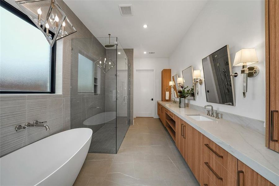 Bathroom with double vanity, a soaking tub, a shower stall, light tile patterned floors, and hanging lights Bathroom with double vanity, a soaking tub, a shower stall, light tile patterned floors, and hanging lights