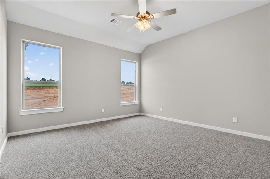 Spacious room featuring vaulted ceilings, light gray wall paint, and gray textured carpeting Spacious room featuring vaulted ceilings, light gray wall paint, and gray textured carpeting
