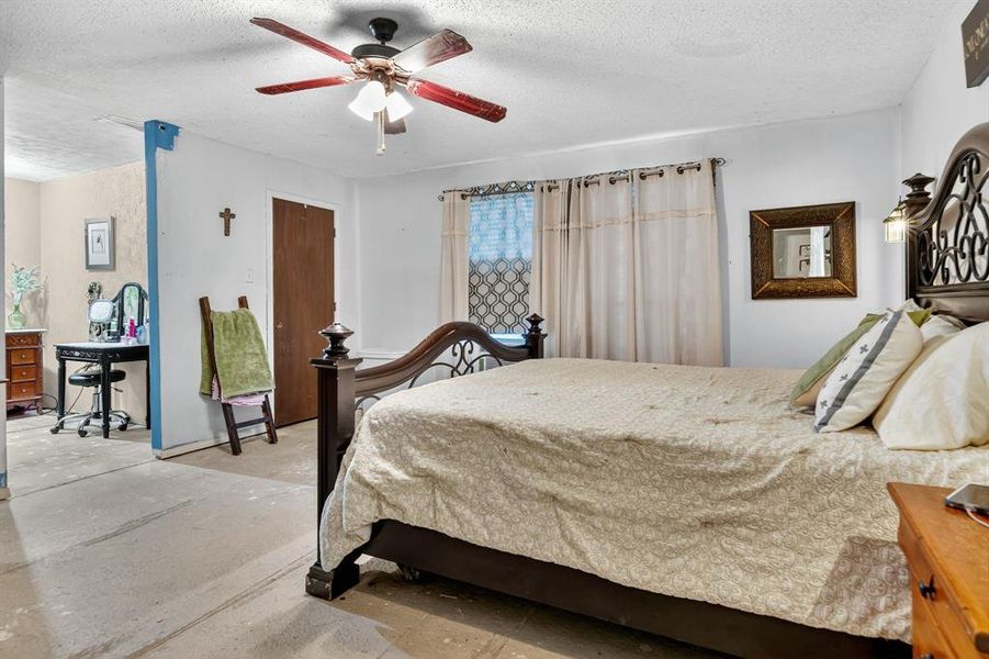 Bedroom featuring a textured ceiling, ceiling fan, and unfinished concrete floors Bedroom featuring a textured ceiling, ceiling fan, and unfinished concrete floors