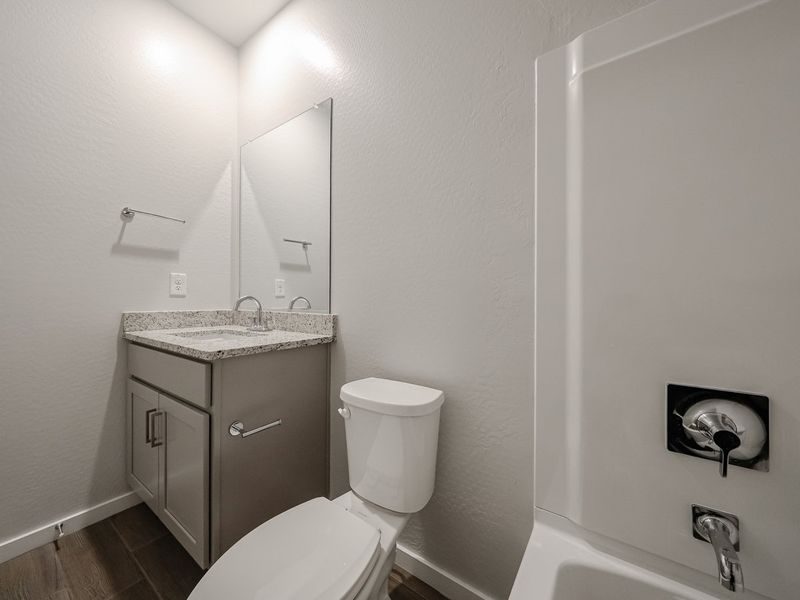 A bathroom with a toilet sink and a mirror.