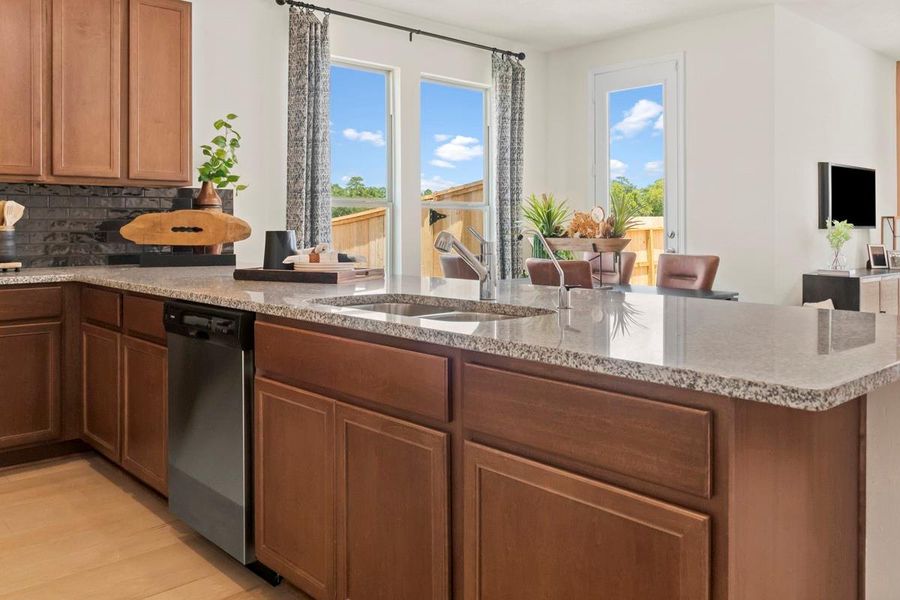 The kitchen features high ceilings, stained Woodmont Cody cabinets, Granite countertops in Luna Pearl, SS appliances, modern tile backsplash, recessed lighting, extended counterspace for breakfast bar, and a pantry all overlooking your huge Great Room.