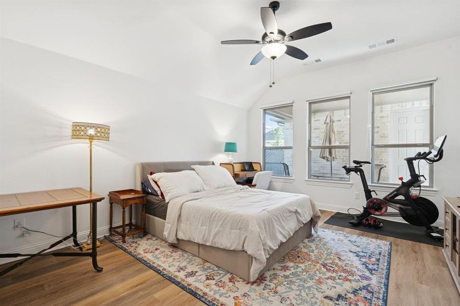 Bedroom featuring light wood finished floors, lofted ceiling, and ceiling fan Bedroom featuring light wood finished floors, lofted ceiling, and ceiling fan