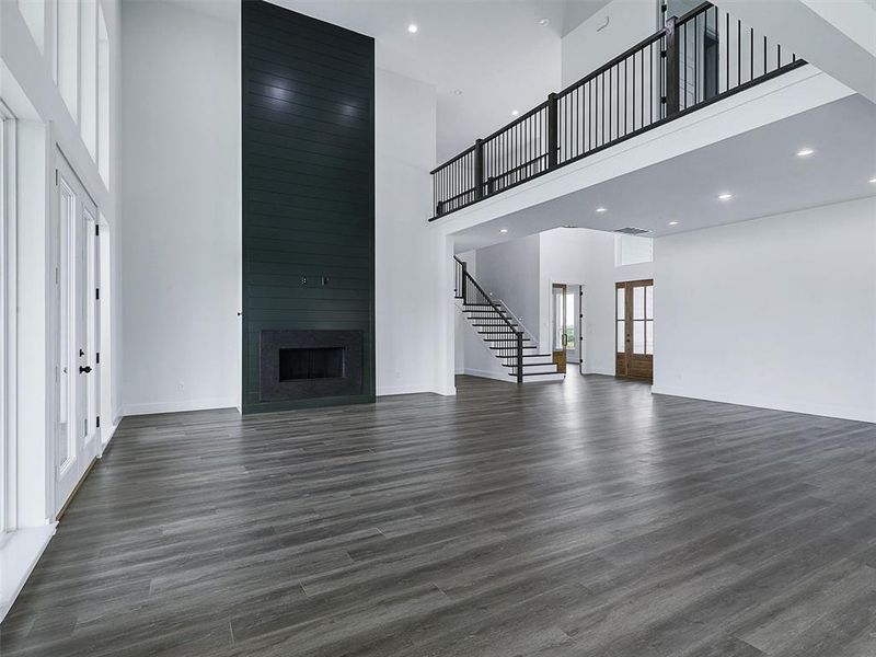 The fireplace is a striking modern focal point that enhances the room’s dramatic two-story design.