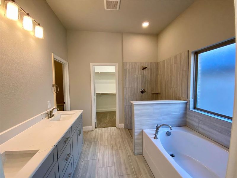 Master bathroom features dual vanity with Monet quartz counters,  12x24 ceramic tile floors & shower walls, and privacy window.