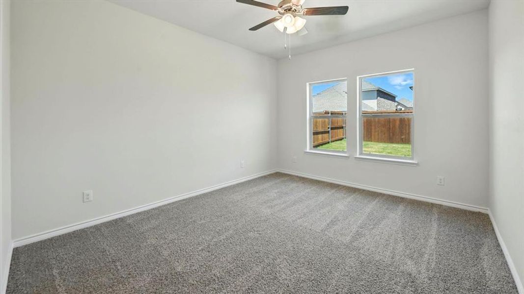 Carpeted empty room featuring baseboards and ceiling fan