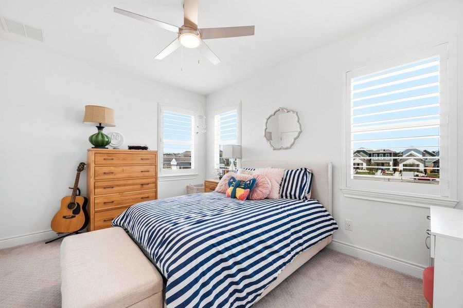Natural light streams through multiple shuttered windows onto plush carpeted flooring. Natural light streams through multiple shuttered windows onto plush carpeted flooring.