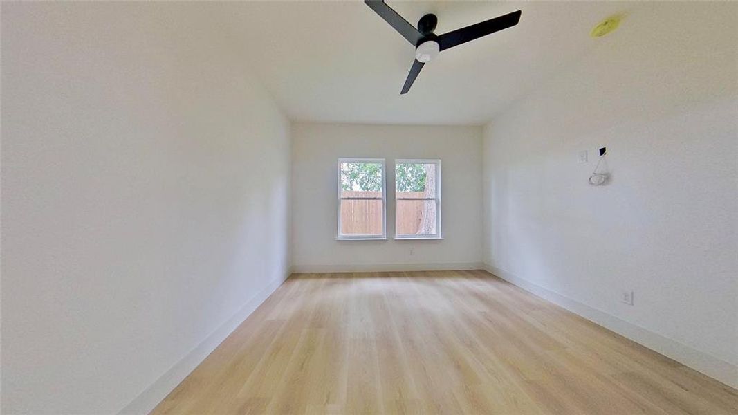 Room featuring wood-finish flooring, white walls, and a contemporary ceiling fan