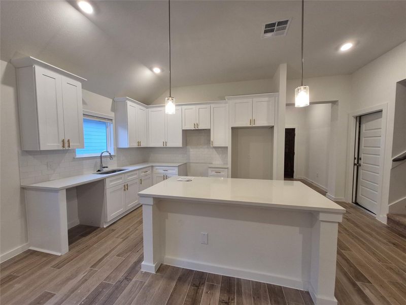Modern kitchen with sleek white cabinetry, elegant pendant lighting, and a spacious center island perfect for entertaining.