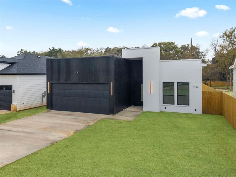 Contemporary home featuring a front yard, driveway, and a garage