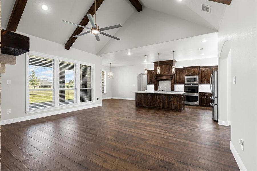 Kitchen featuring arched walkways, high vaulted ceiling, dark brown cabinets, light countertops, and open floor plan Kitchen featuring arched walkways, high vaulted ceiling, dark brown cabinets, light countertops, and open floor plan