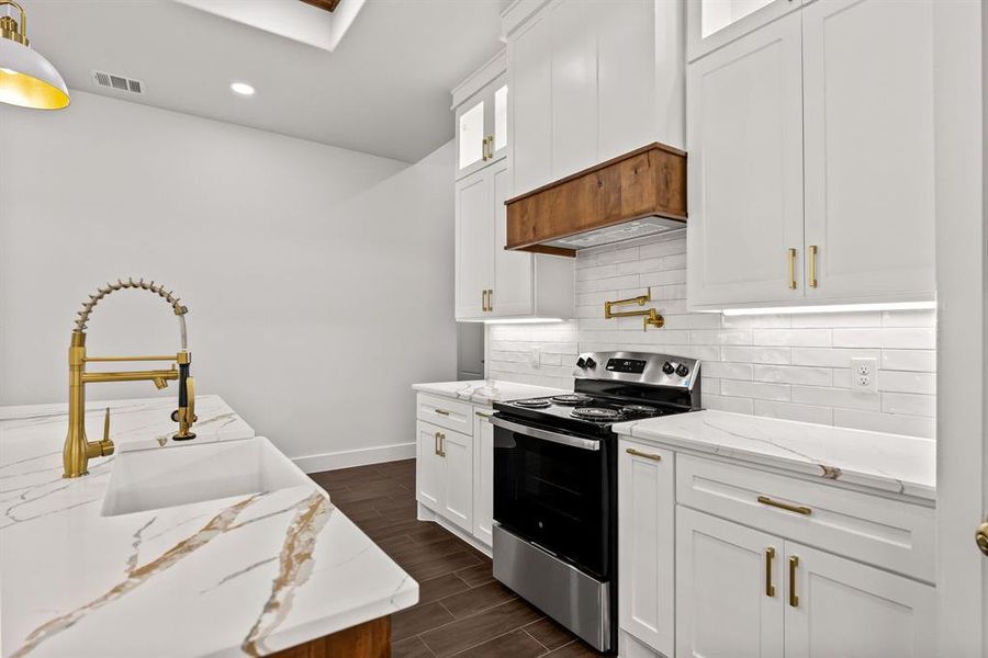 Kitchen featuring stainless steel range with electric cooktop, wood tiled floors, white cabinetry, glass insert cabinets, and tasteful backsplash Kitchen featuring stainless steel range with electric cooktop, wood tiled floors, white cabinetry, glass insert cabinets, and tasteful backsplash